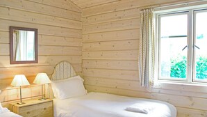 A wooden cabin room with two beds, a nightstand, a mirror, and a window with curtains. - Curlew Lodge - UK51677 (Dumfries and Galloway)