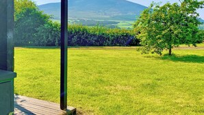 A grassy field with a mountain in the background and a wooden structure in the foreground. - Curlew Lodge - UK51677 (Dumfries and Galloway)