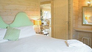 Una habitación de madera con una cama, una silla, una mesa y un espejo.