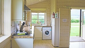 Cocina compacta con lavadora, lavaplatos y ventana con vistas al verdor.