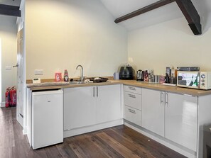A compact kitchen with a dishwasher, sink, and various appliances including a coffee maker and a microwave.