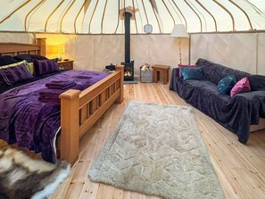 A cozy interior with a bed, sofa, rug, and a wood-burning stove.