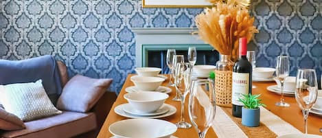 A dining table set with white plates, bowls, and wine glasses, a bottle of CÎTELIER wine, and a small potted plant.