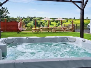 A hot tub with a view of a grassy area, picnic tables, and a wooden fence. - Great Farmhouse with private hot tub and sauna, perfect for families. (llanbister)