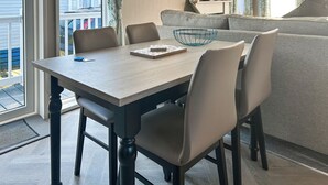 Un coin repas avec une table en bois, quatre chaises, un bol et un livre.