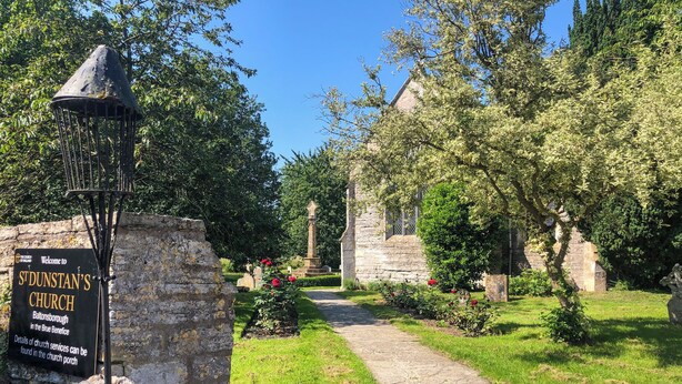 A church entrance with a sign, a stone pathway, and surrounding greenery. - 1 bedroom accommodation in Somerset, Glastonbury, Street, Shepton Mallet (Somerset, Glastonbury, Street, Shepton Mallet)