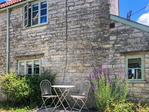 A stone building with a small table and two chairs outside. - 1 bedroom accommodation in Somerset, Glastonbury, Street, Shepton Mallet (Somerset, Glastonbury, Street, Shepton Mallet)