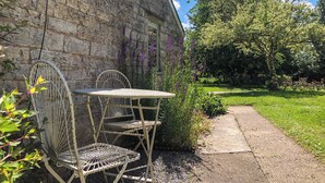 A stone building with a garden path, outdoor seating with metal chairs and a table, and a variety of plants and flowers. - 1 bedroom accommodation in Somerset, Glastonbury, Street, Shepton Mallet (Somerset, Glastonbury, Street, Shepton Mallet)