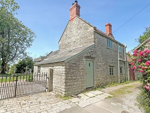 A stone building with a green door, a small window, and a chimney. - 1 bedroom accommodation in Somerset, Glastonbury, Street, Shepton Mallet (Somerset, Glastonbury, Street, Shepton Mallet)