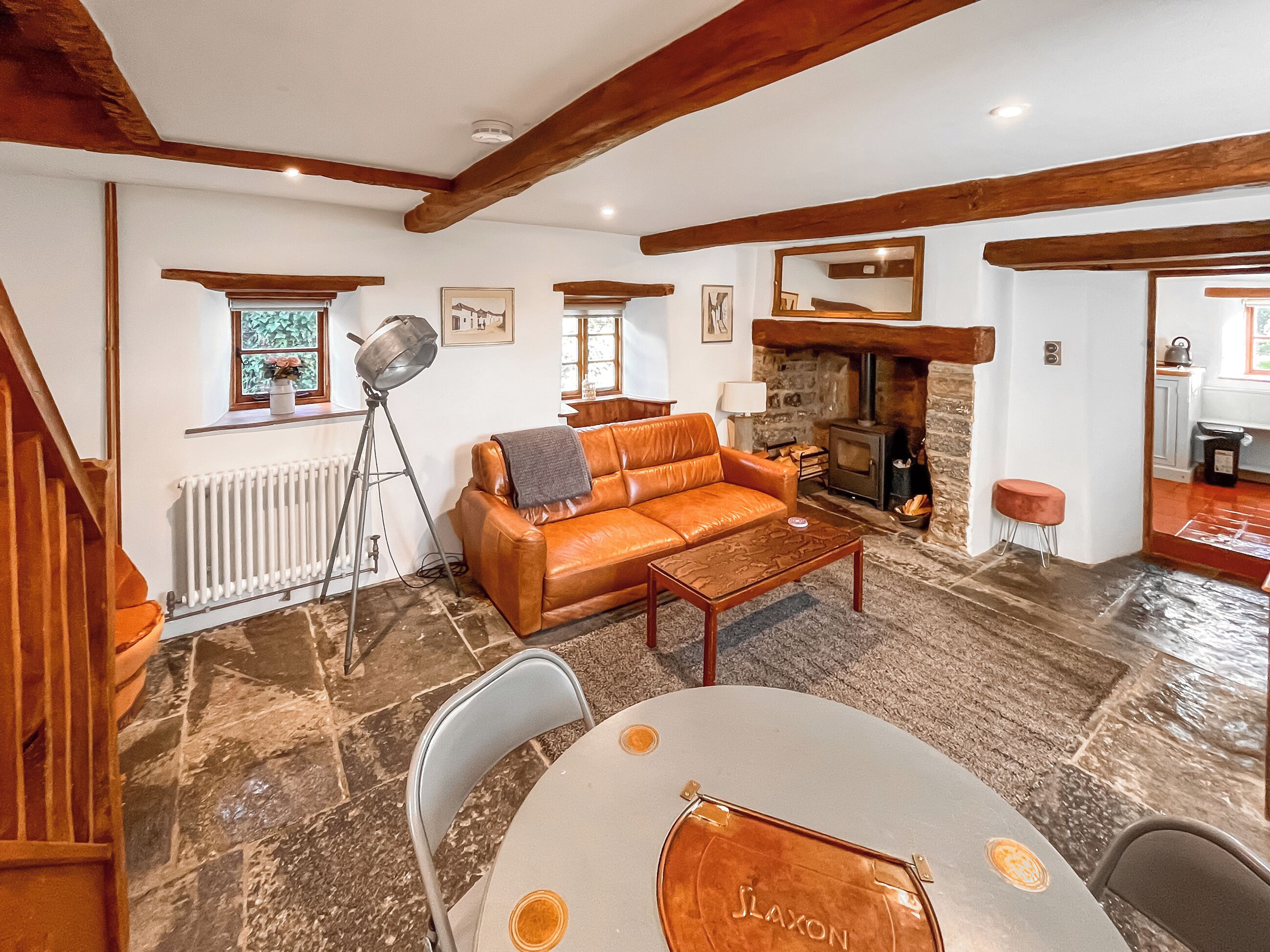 Una sala de estar acogedora con un sofá de cuero, una chimenea de piedra y un comedor con mesa y sillas.