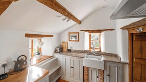 A kitchen with wooden beams, white cabinets, a sink, a toaster, and a window with a view. - 1 bedroom accommodation in Somerset, Glastonbury, Street, Shepton Mallet (Somerset, Glastonbury, Street, Shepton Mallet)