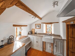 A kitchen with wooden beams, white cabinets, a sink, a toaster, and a window with a view. - 1 bedroom accommodation in Somerset, Glastonbury, Street, Shepton Mallet (Somerset, Glastonbury, Street, Shepton Mallet)