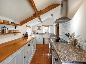 A kitchen with wooden beams, white cabinets, and a granite countertop. - 1 bedroom accommodation in Somerset, Glastonbury, Street, Shepton Mallet (Somerset, Glastonbury, Street, Shepton Mallet)