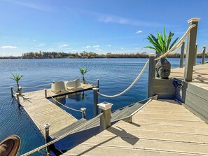 Un muelle de madera con una pequeña piscina, plantas en macetas y una estatua de Buda.