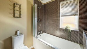 Un baño con inodoro, ducha con puerta de cristal y ventana con persianas.