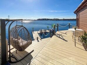A wooden deck with a hanging chair, a small pool, and a Buddha statue.