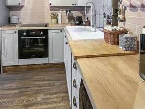 Una cocina con horno Bosch, un lavamanos y una encimera de madera.