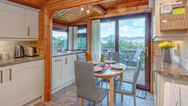 A wooden cabin with a kitchen and dining area, large windows, and a view of mountains. - 2 bedroom accommodation in Trawsfynydd (Trawsfynydd)