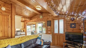 A wooden cabin interior with a sofa, television, kitchen, and dining area. - 2 bedroom accommodation in Trawsfynydd (Trawsfynydd)