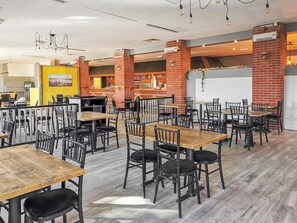Ein geräumiges Restaurant mit mehreren Tischen, Stühlen, einer Bar und einer Tafel an der Wand.