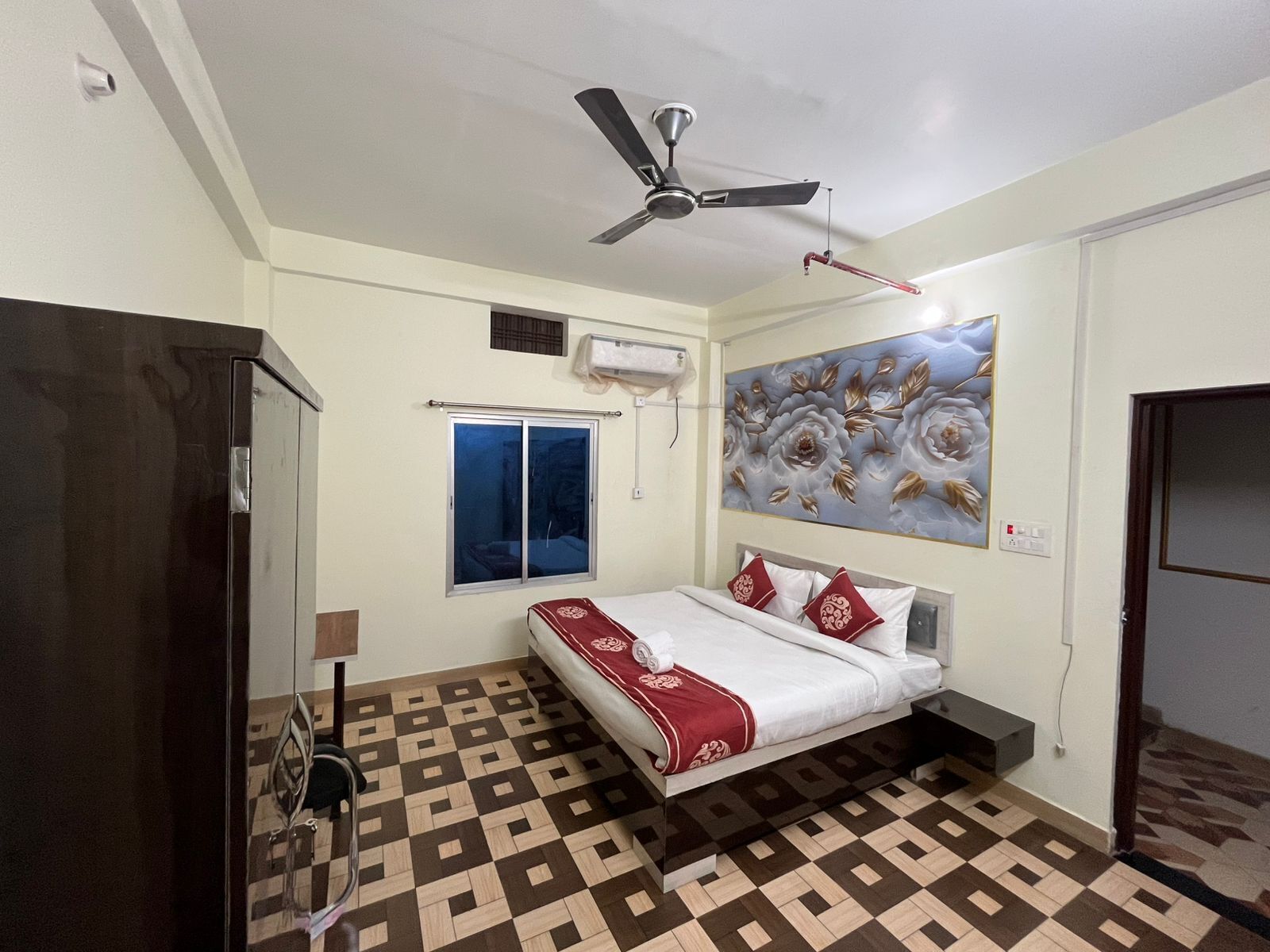 Un dormitorio con cama, ventilador de techo, ventana y aire acondicionado instalado en la pared.