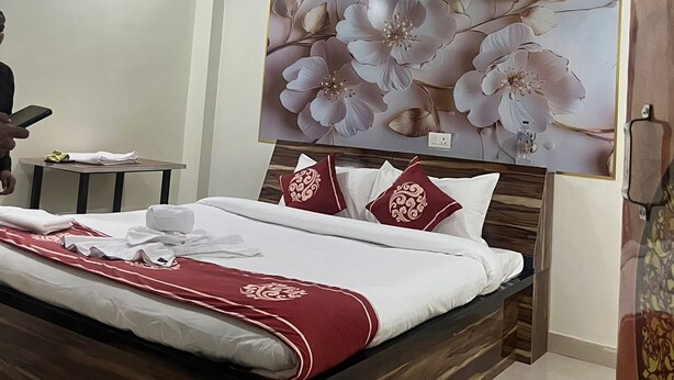 Ein Schlafzimmer mit einem Bett, einem Deckenventilator, einem Wandbild mit Blumen und einem Nachttisch mit Lampe.