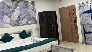 Ein Hotelzimmer mit Bett, Schreibtisch, Stuhl, Deckenventilator, Kleiderschrank und einem großen Wandbild.