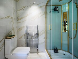 Ein Badezimmer mit Toilette, einer Duschkabine und einer Marmorwand.