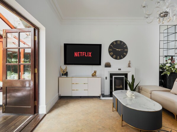 A living room with a TV, a fireplace, a sofa, and a door.