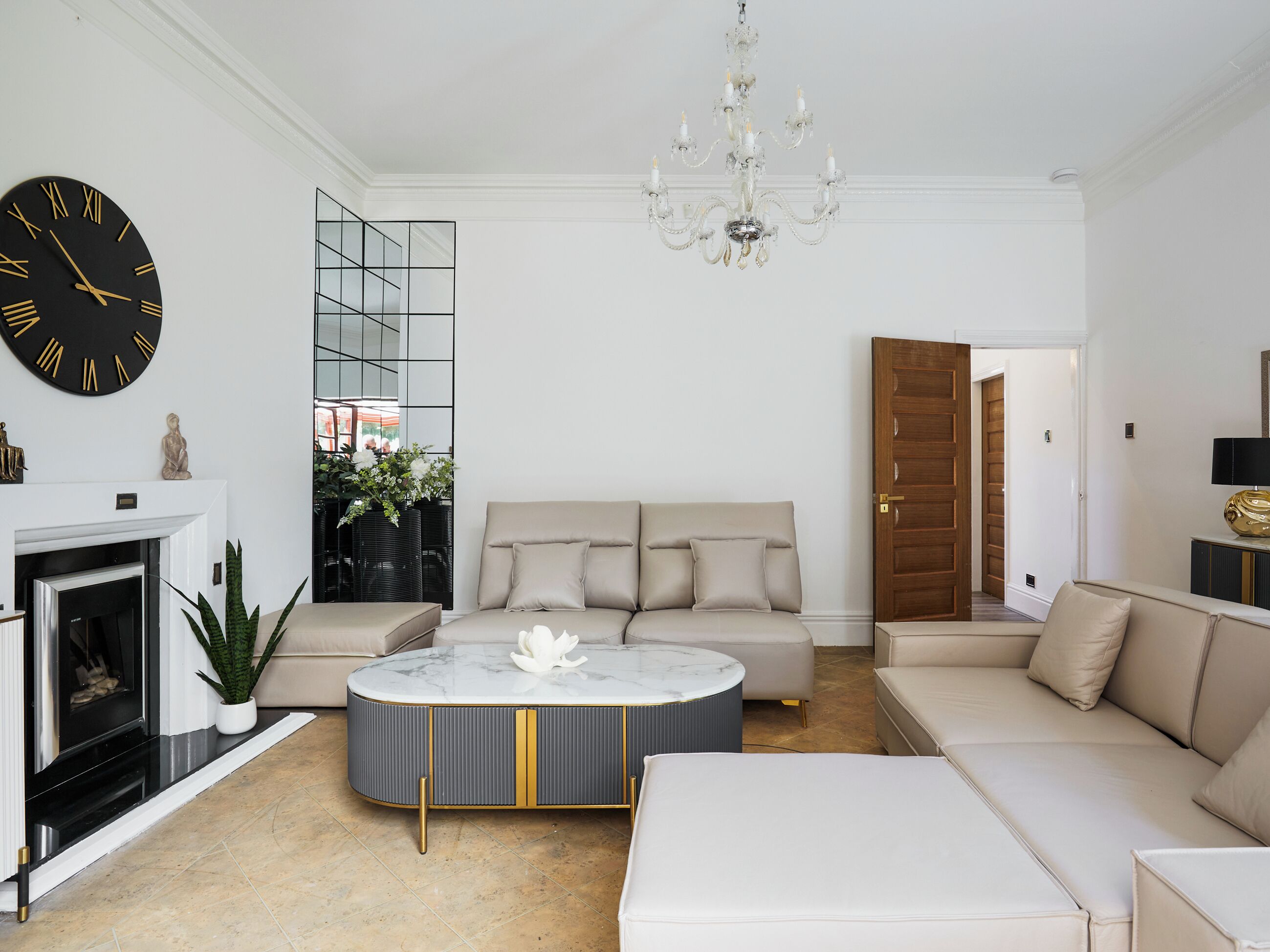 A living room with a sofa, a coffee table, a fireplace, and a large wall clock.