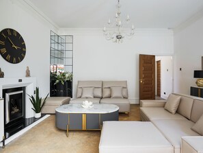 A living room with a sofa, a coffee table, a fireplace, and a large wall clock.