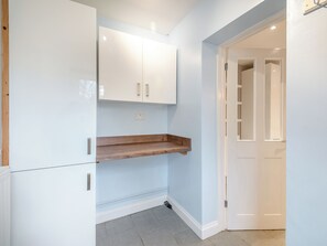 A room with a white cabinet, a wooden shelf, a white door, and a light blue wall. - 1 bedroom accommodation in Castle Bytham, near Grantham (Castle Bytham, near Grantham)