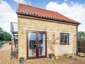 A stone building with a tiled roof, a glass door, and a small window. - 1 bedroom accommodation in Castle Bytham, near Grantham (Castle Bytham, near Grantham)