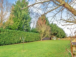 A well-maintained garden with a variety of trees, a neatly trimmed hedge, and a small wooden structure. - 1 bedroom accommodation in Castle Bytham, near Grantham (Castle Bytham, near Grantham)