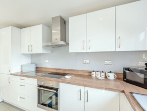 A modern kitchen with white cabinets, a built-in oven, a microwave, and a stainless steel range hood. - 1 bedroom accommodation in Castle Bytham, near Grantham (Castle Bytham, near Grantham)