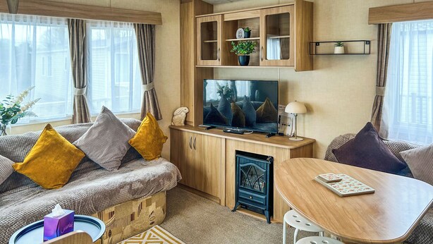 Ein gemütlicher Wohnbereich mit einer Couch, einem Fernseher, einem kleinen Tisch und einem dekorativen Herd.