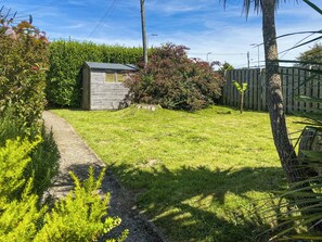 A garden with a wooden shed, a paved path, and a wooden fence. - 2 bedroom accommodation in Woolacombe (Woolacombe)