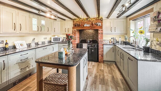 Una cocina con una isla central, armarios blancos, una chimenea de ladrillo y un letrero que dice 'The Family'.