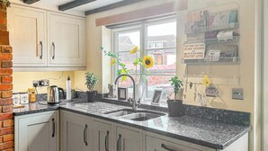 Cocina con encimeras de granito, un lavamanos doble y ventana con vista a casas.