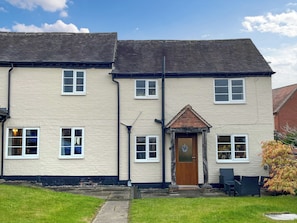 A two-story building with a central entrance, multiple windows, and a small porch area. - 2 bedroom accommodation in Walton On Trent (Walton On Trent)