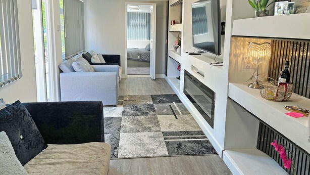 A modern living room with a sofa, TV, and decorative items.
