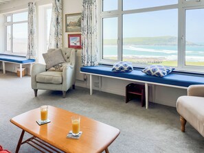 A room with a view of the sea, a sofa, a chair, and a table with glasses of orange juice. - 6 bedroom accommodation in Trebetherick, near Wadebridge (Trebetherick, near Wadebridge)