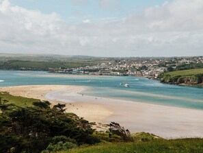 A coastal town with a sandy beach, a bay with boats, and a backdrop of houses and greenery. - 6 bedroom accommodation in Trebetherick, near Wadebridge (Trebetherick, near Wadebridge)