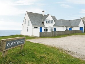 A coastal house with a gravel driveway, a wooden fence, and a sign reading 'Corncocks.' - 6 bedroom accommodation in Trebetherick, near Wadebridge (Trebetherick, near Wadebridge)
