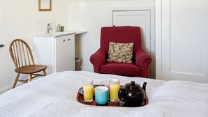 A neatly arranged room with a bed, a chair, a small cabinet, and a door. - 6 bedroom accommodation in Trebetherick, near Wadebridge (Trebetherick, near Wadebridge)