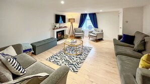Ein modernes Wohnzimmer mit einer Couch, Sesseln, einem Couchtisch und einem Kamin.