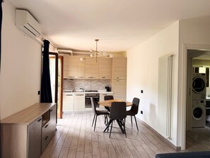 A modern kitchen with wooden cabinets, a dining area with a table and chairs, and a built-in washing machine. - Casa Adri (Molina)