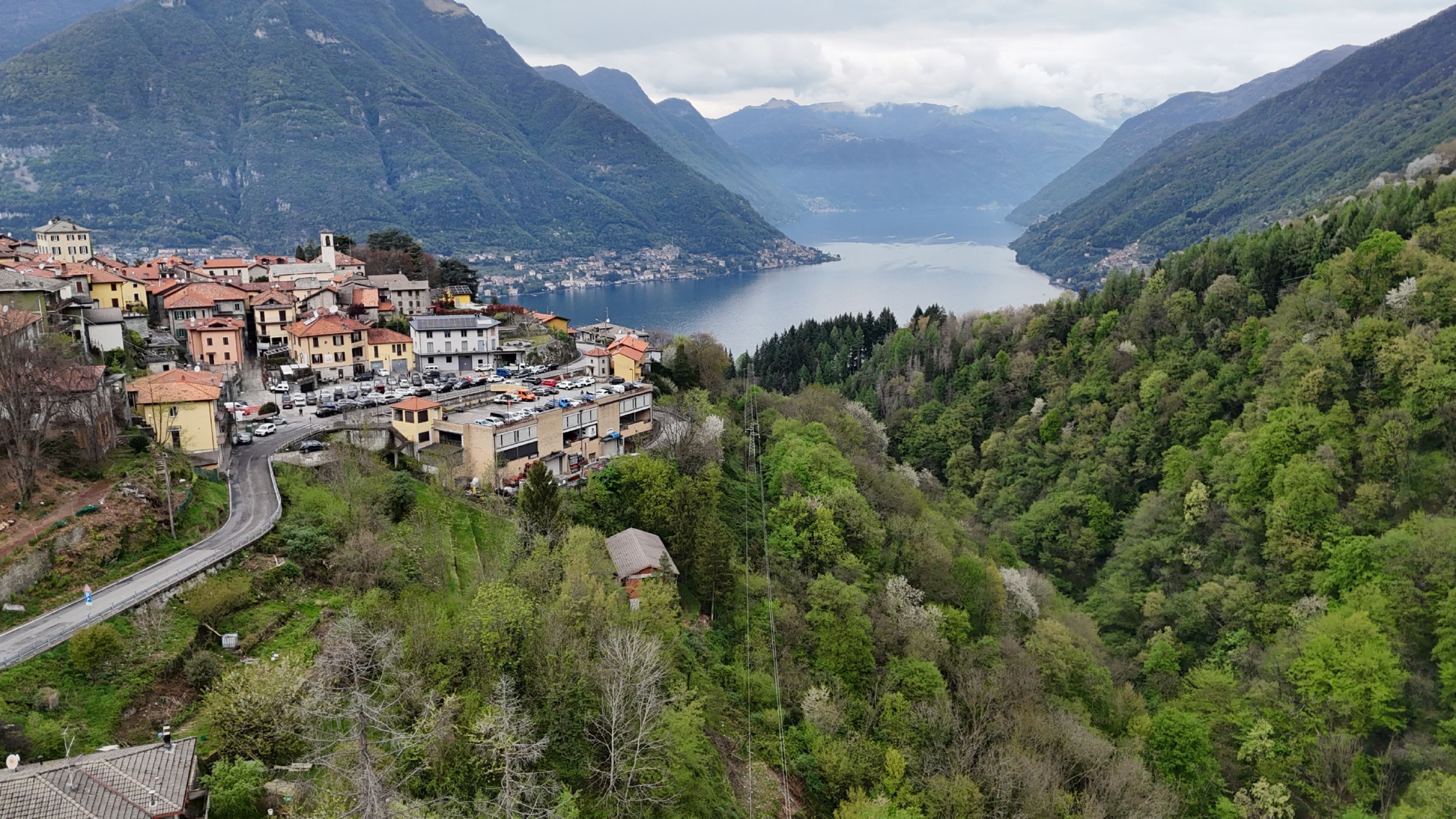 A mountainous town with a lake, featuring a mix of residential buildings and a parking area.