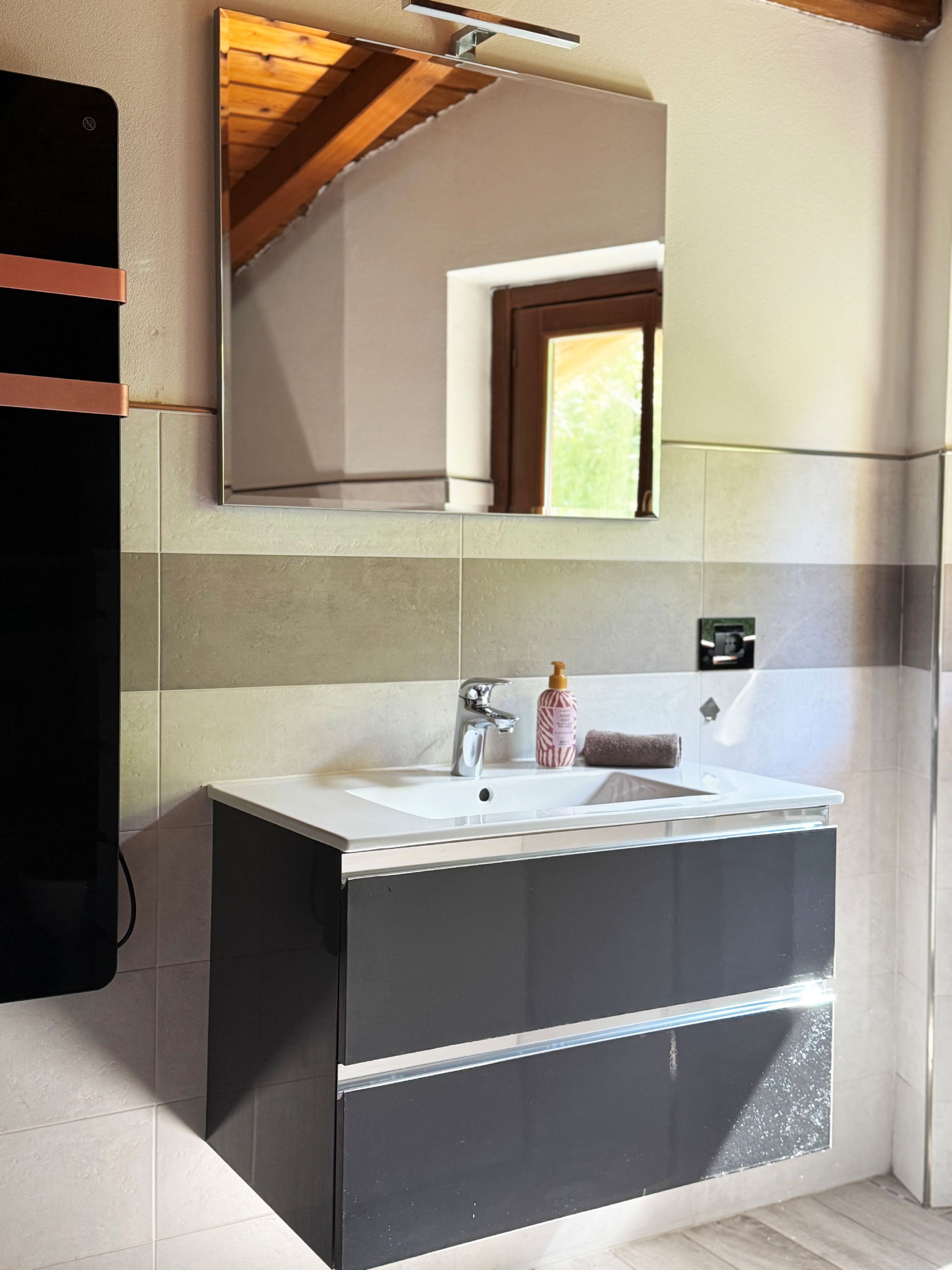 Un baño moderno con un espejo grande, un lavabo y un perchero para toallas.