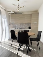A modern kitchen with a central island, black chairs, and a ceiling light fixture.